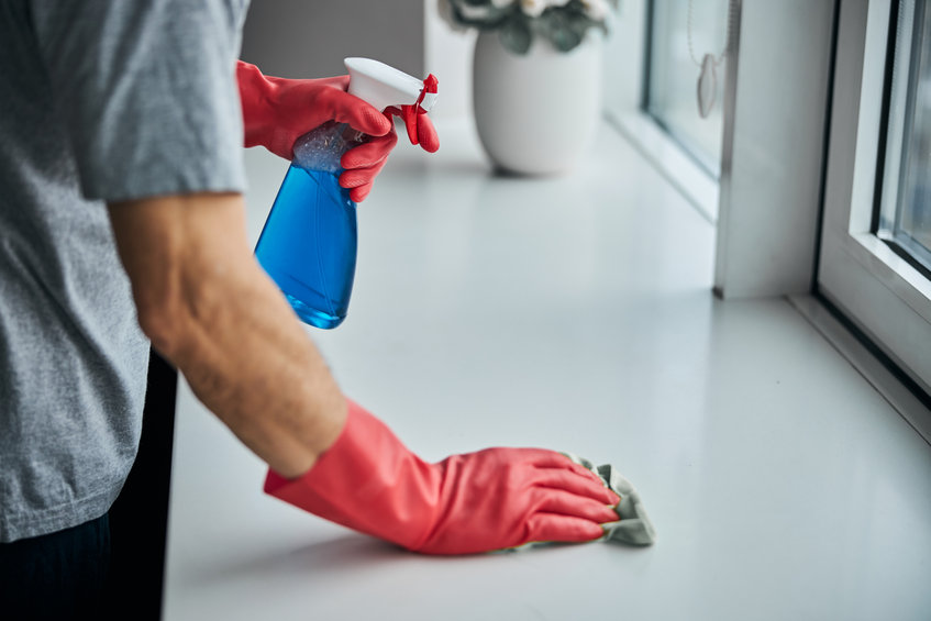 man cleaning and disinfecting surface of window-sill