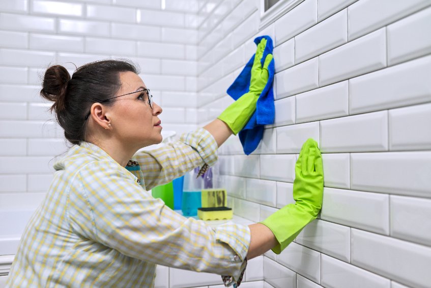 a woman cleaning a bathroom with gloves on
